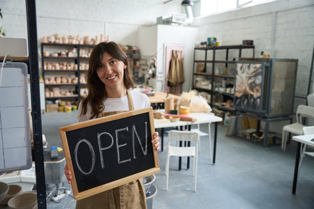 Woman holding an open sign in her handsの写真素材