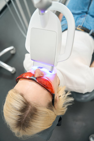 Caucasian female patient in goggles undergoing teeth whitening procedureの写真素材