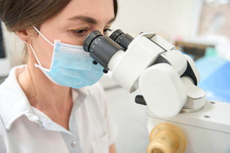 Lady doctor looks into the microscope closeupの写真素材