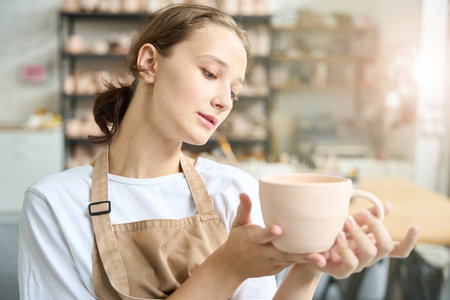 Young woman is examines homemade clay cupの写真素材