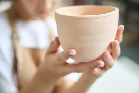 Close-up of a large clay cup in female handsの写真素材
