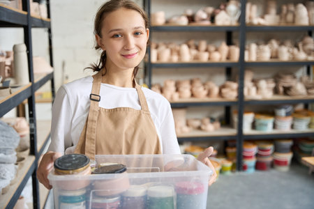 Student is holding plastic box with paints in her handsの写真素材