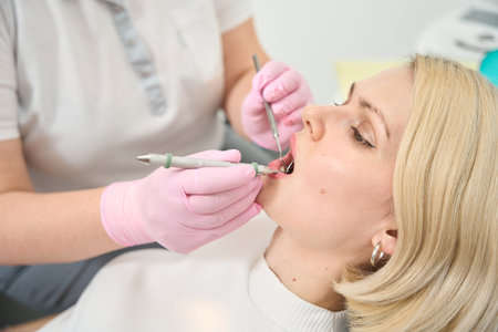 Patient sitting with open mouth during dental treatmentの写真素材