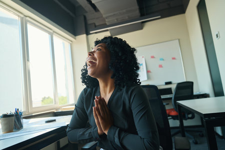 Joyful woman sits in chair with her hands folded in prayer