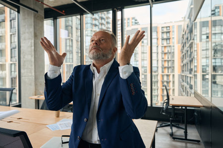 Mature male businessman celebrating success at workの写真素材