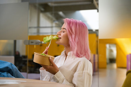 Young lady having lunch in the officeの写真素材