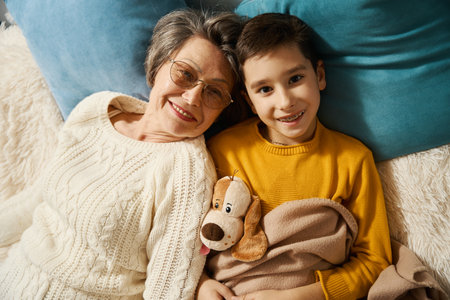 Old lady resting with her grandson on bedの写真素材