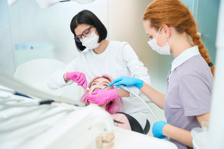 Woman dentist performs a dental procedure to a young patientの写真素材