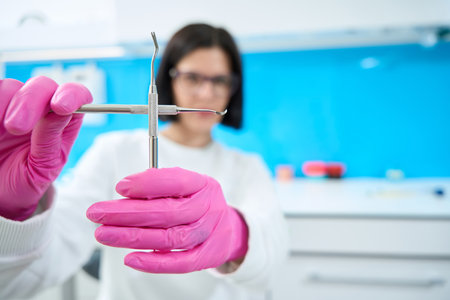 Woman in protective gloves holds dental instruments in her handsの写真素材