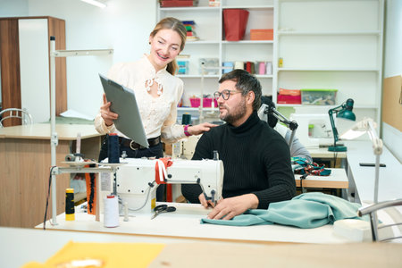 Woman with a tablet is standing at the tailors workplace
