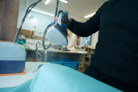 Man holds a modern steam iron in his handsの写真素材
