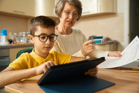 Kid helping granny shopping online, use credit cardの写真素材