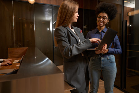 Portrait of administrator showing lady information in laptopの写真素材