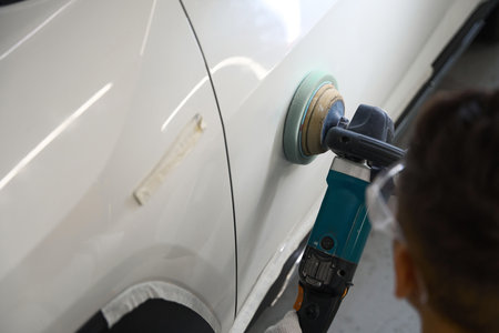 Close up photo of mechanic polishing car in garage