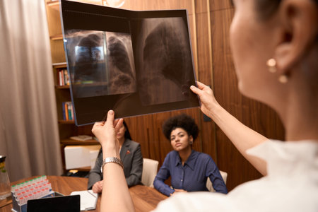 Woman in medical clothes examining x-ray of patient in clinic