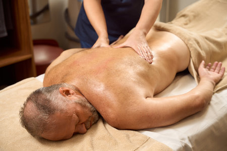 Elderly man undergoes a course of wellness massage for backの写真素材