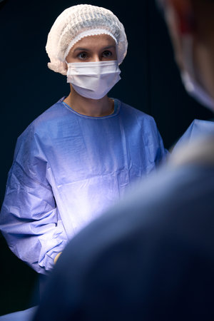 Female in surgical sterile uniform stands under light of lampの写真素材