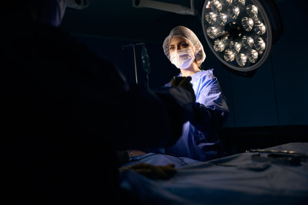 Female in a protective mask stands at the operating tableの写真素材