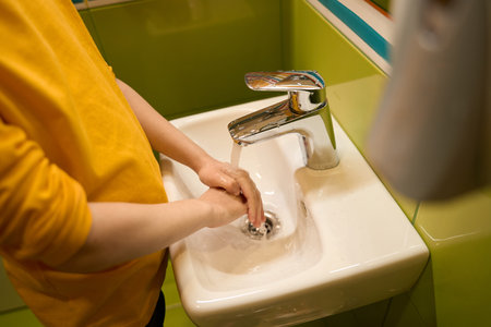 Neat child is cleaning his arms in the washroomの写真素材