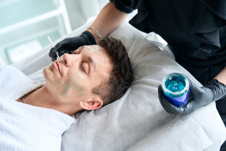 Female apply revitalizing mask for face on man skinの写真素材
