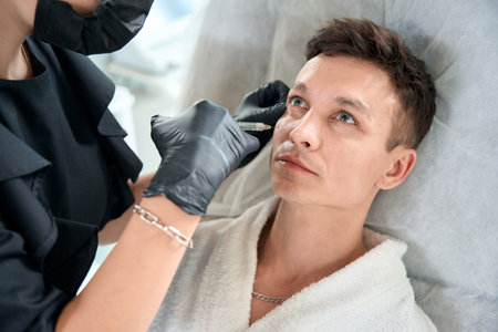 Male in beauty clinic getting face injectionの写真素材