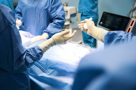 Man in operating room passing surgical instrument to colleagueの写真素材