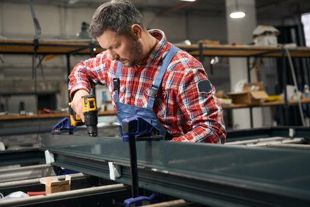 Adult male connecting metal parts in factory