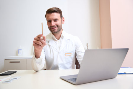 Gorgeous Caucasian doctor sitting at the work desk in the medical cabinetの写真素材