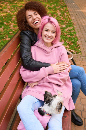 Happy lesbian couple spending time with dog in public parkの写真素材