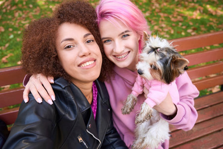 Two joyful ladies taking selfie with their Yorkshire Terrier outdoorsの写真素材