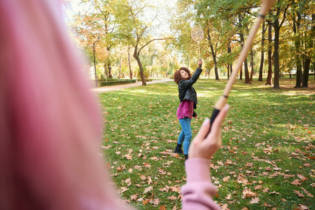 Two people playing badminton on lawn in parkの写真素材