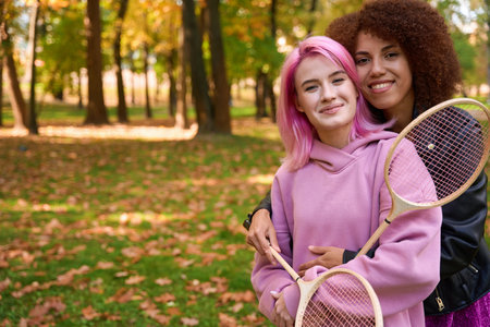 Romantic lesbian couple with badminton rackets standing outdoorsの写真素材