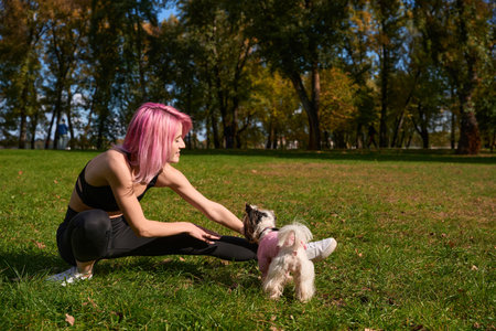 Smiling sportswoman performing leg stretch in public parkの写真素材