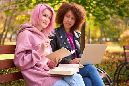 Lady watching her smiling friend writing ideas in notebookの写真素材