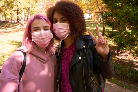 Two ladies in face masks posing for camera during walkの写真素材