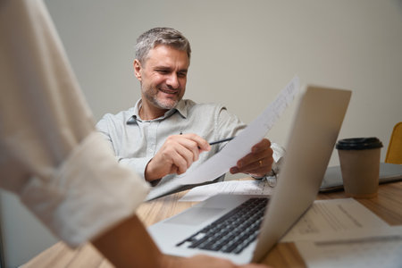 Smiling man working in office, talking to colleagueの写真素材