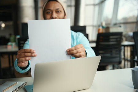 Male in hat holding piece of paper