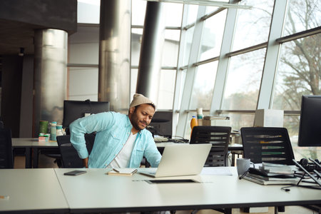Man in hat kneading his back at jobの写真素材