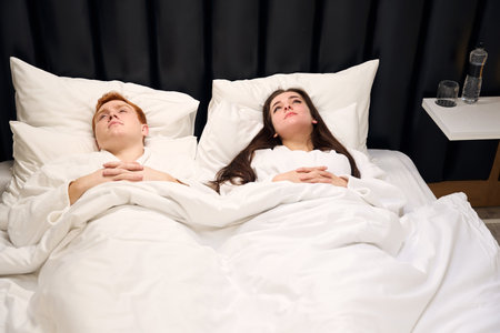 Tired guy and his girlfriend are resting in soft bedの写真素材