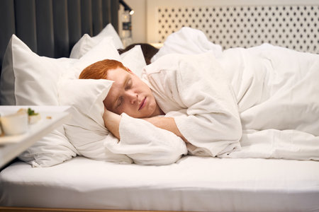 Young married couple sleeps sweetly on a large hotel bedの写真素材