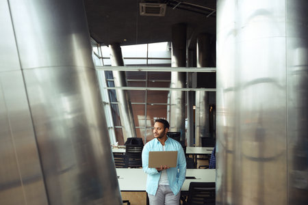Man with laptop in his hands looking out windowの写真素材