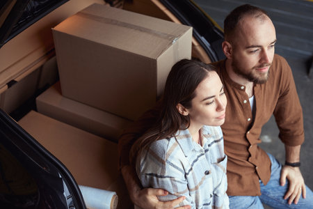 Young calm couple sitting in the trunk of a car