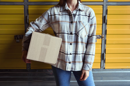 Neat woman holding the cardboard box in the storageの写真素材