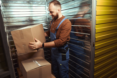 Glad young man holding box in the storage