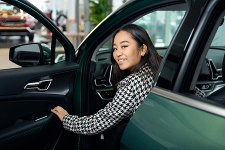 Happy young lady is sitting in drivers seat in new carの写真素材