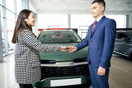 Asian woman takes car keys from man in business suitの写真素材