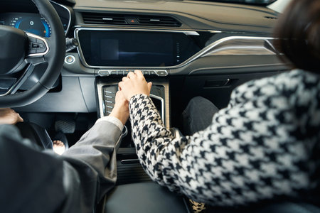 Two female hands in suits laying on automobile gearbox
