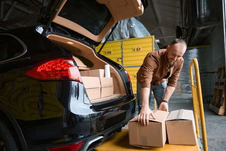 Joyful young male taking a box from a dipperの写真素材