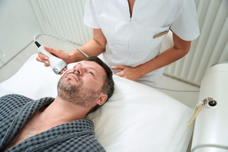 Nurse treating male in the beauty salonの写真素材