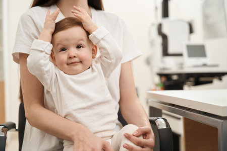 Happy baby with mother at pediatric ophthalmologist officeの写真素材